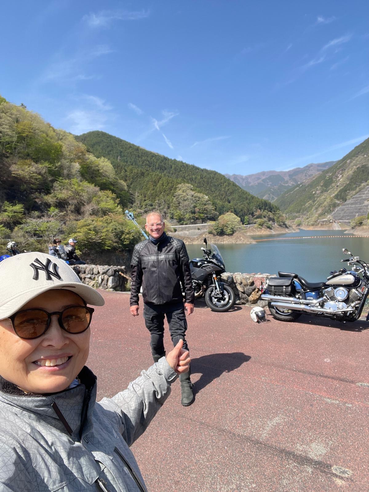 Motorrad-Tour an einem Bergsee in Japan mit Blick auf bewaldete Berge