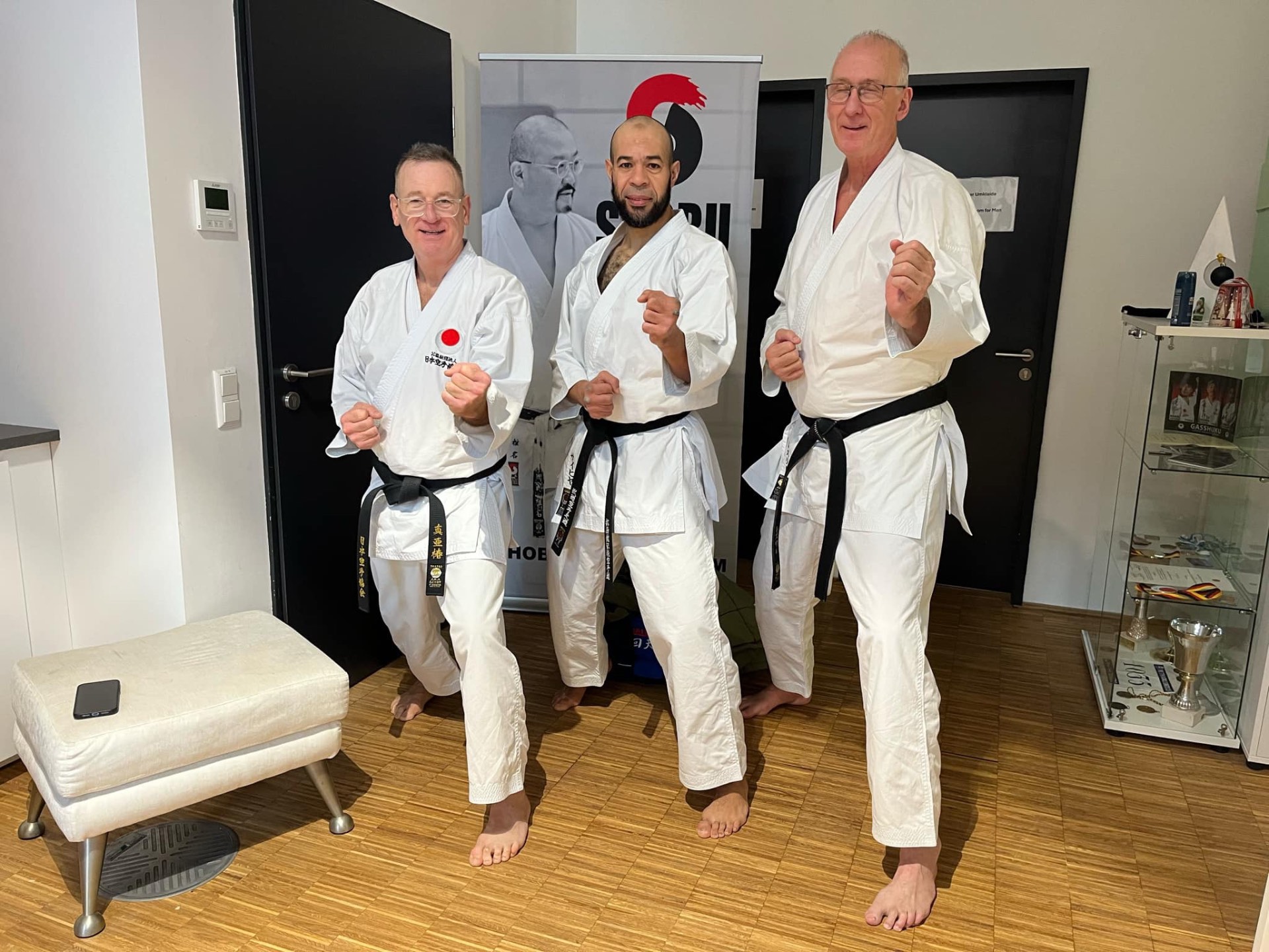 Drei Schwarzgurte in Kamae vor dem Sensei-Rollup