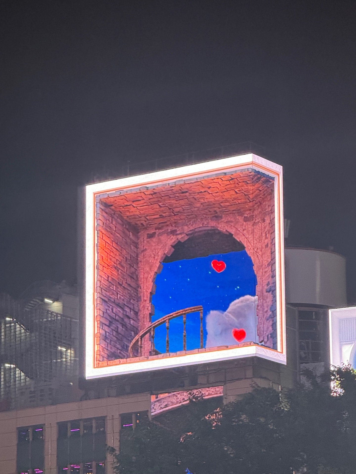 3D-LED-Billboard mit Backsteintor und schwebenden roten Herzen über Shinjuku bei Nacht