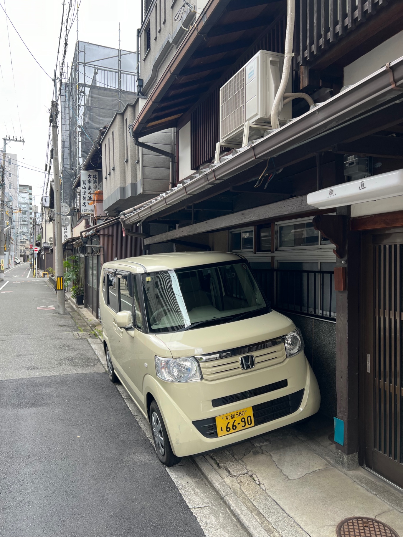 Schmale Straße in Kyoto mit traditioneller Fassade und hellem Kei-Van