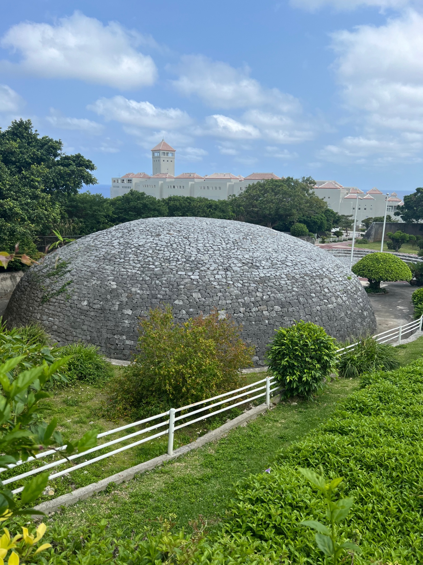 Historische Steinkuppel mit weißer Burg im Hintergrund auf Okinawa