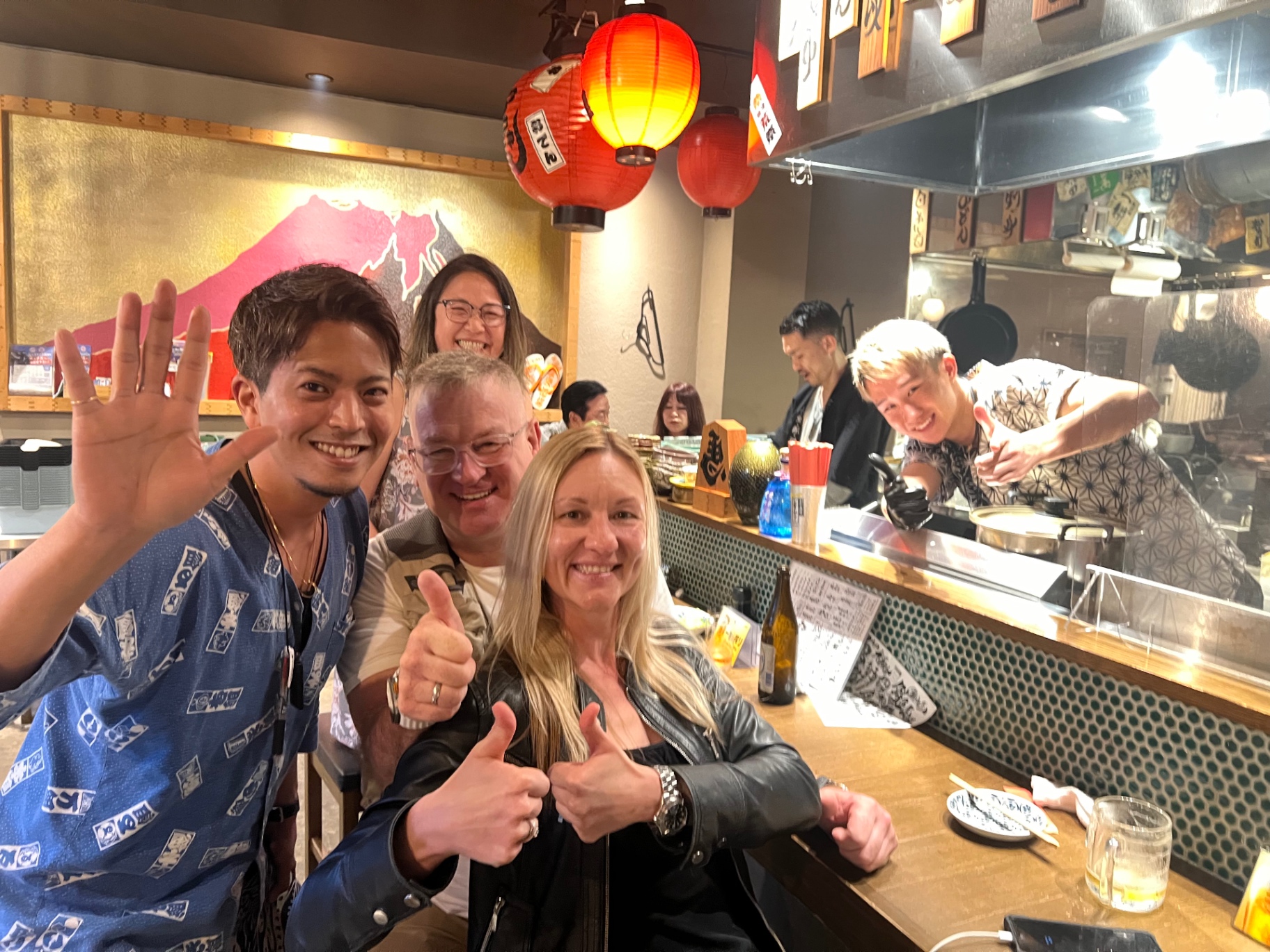 Fröhliches Gruppenfoto in einer Izakaya unter roten Laternen in Japan