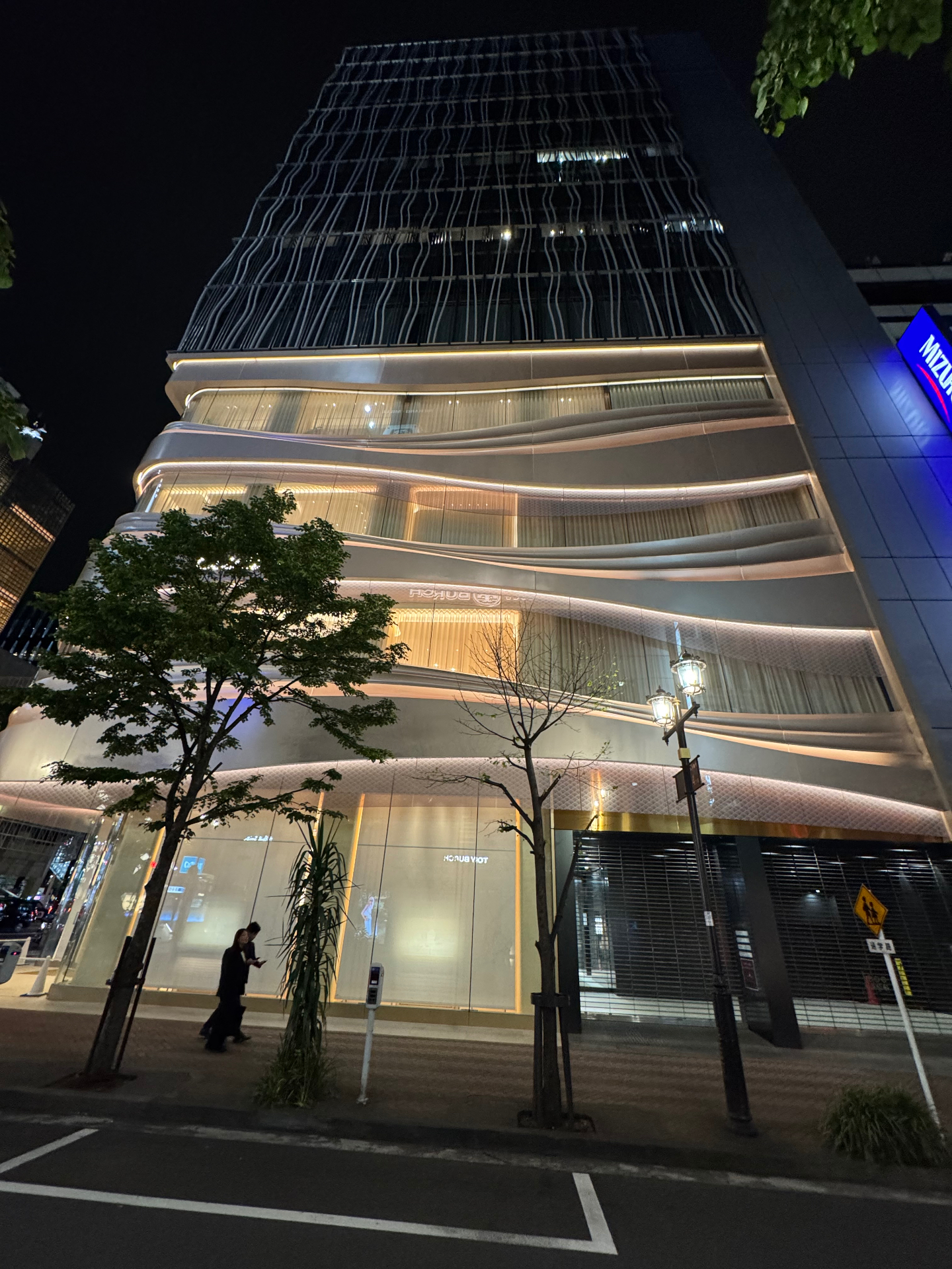Hochhausfassade mit geschwungener Wellenstruktur in Ginza bei Nacht